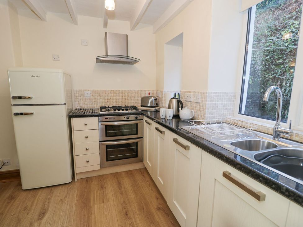 A kitchen with stove, sink, and refrigerator at Ty Gwyn Aberdovey