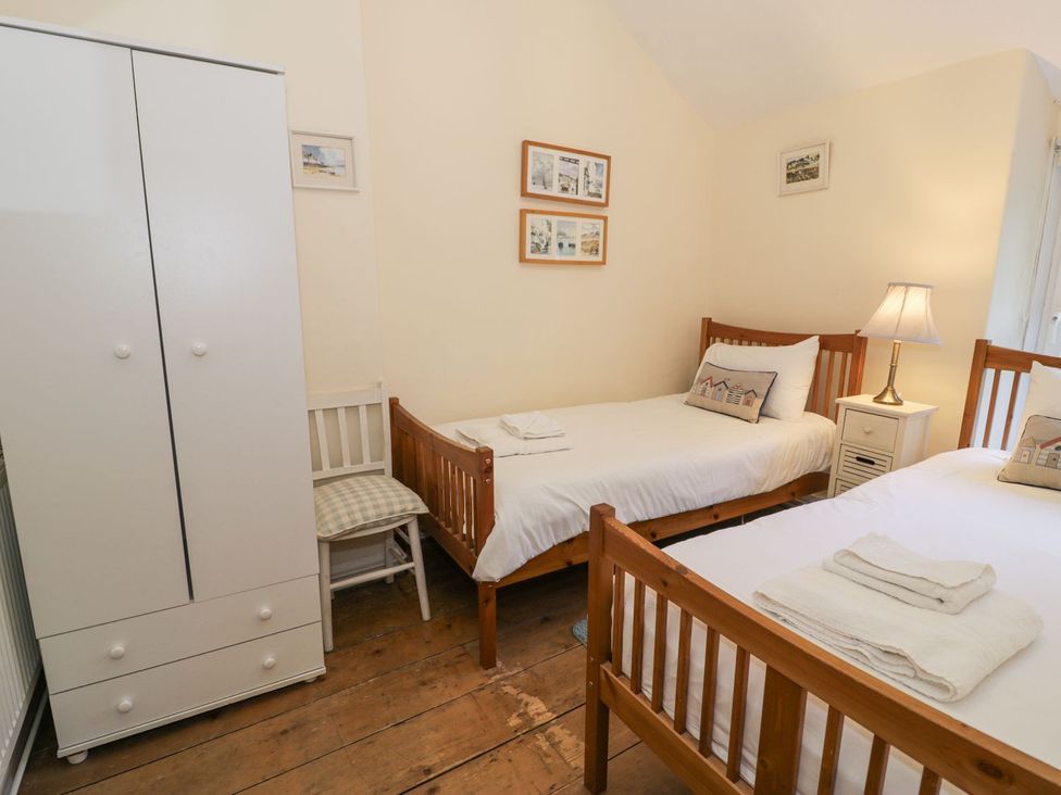 A bedroom with two beds and a wardrobe at Ty Gwyn in Aberdovey
