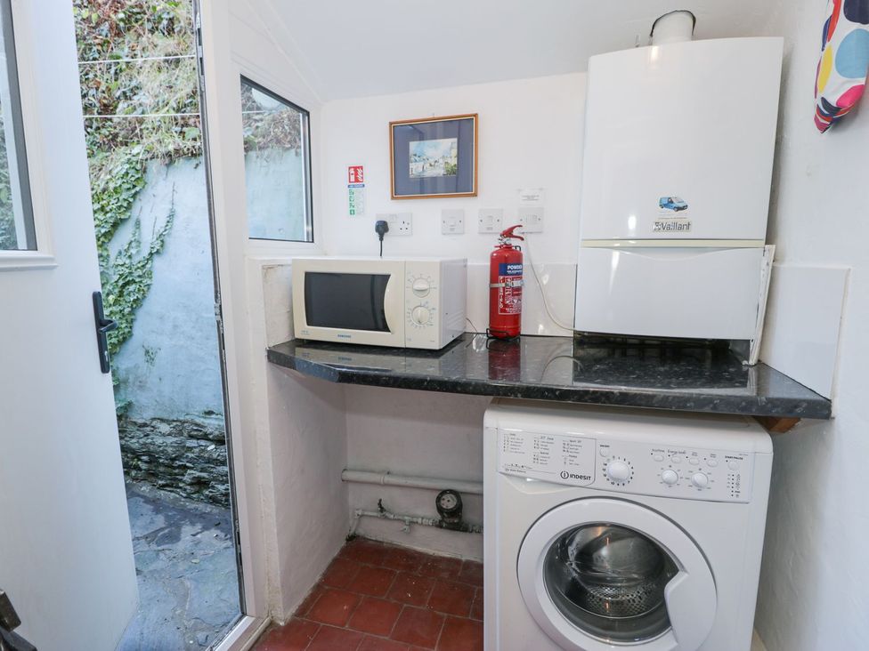 A laundry room with a washing machine and microwave at Ty Gwyn in Aberdovey