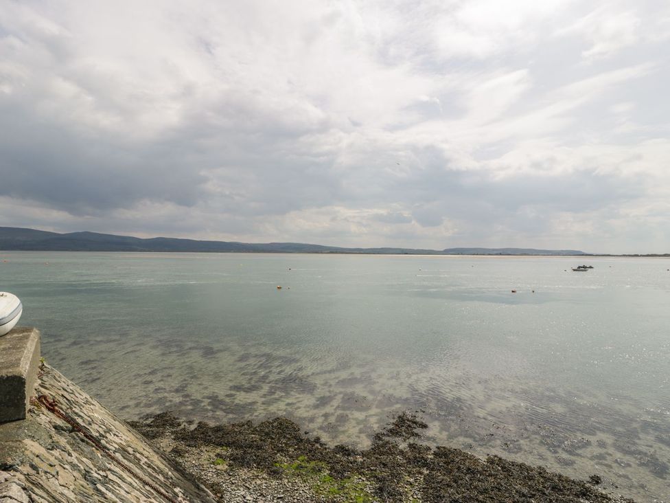 A view of water with a boat on the surface and rocky shoreline at Ty Gwyn in Aberdovey