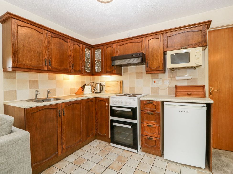 A kitchen with wooden cabinets and appliances at Oak Tree in Weston-super-Mare