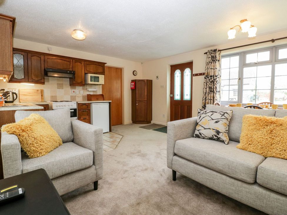 A living room with a dining table and kitchen units at Oak Tree in Weston-super-Mare