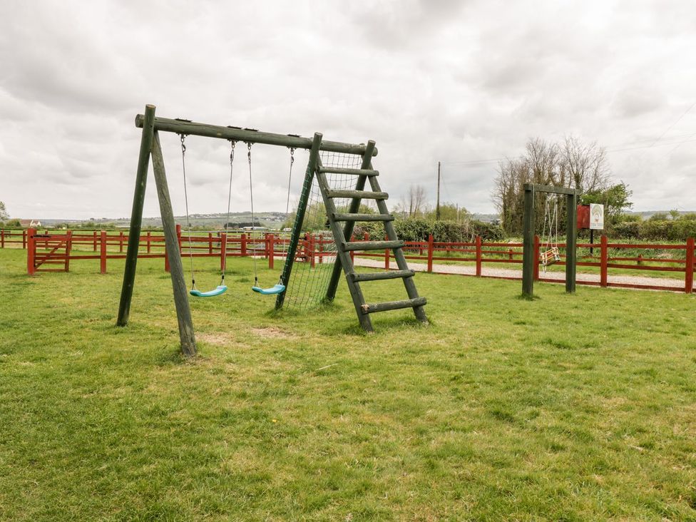 A swing set and climbing frame in an outdoor playground at Oak Tree in Weston-super-Mare