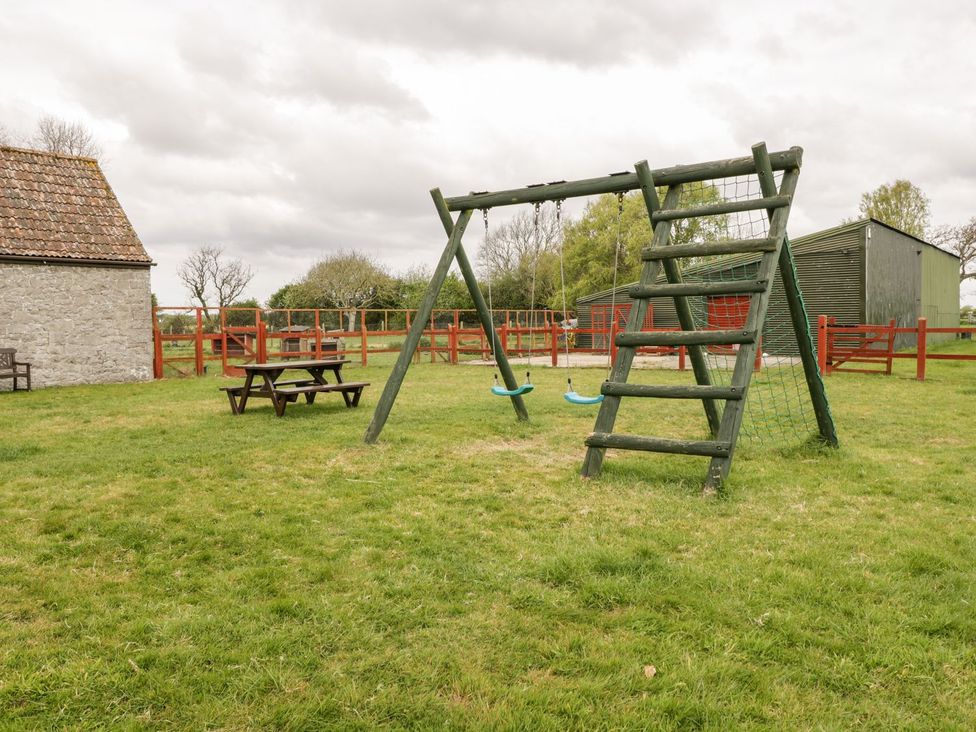 An outdoor area with a swing set and picnic table at Oak Tree in Weston-super-Mare