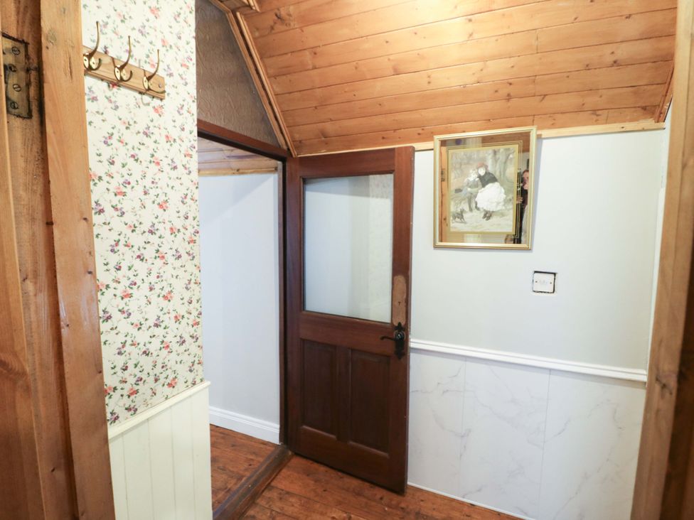 A hallway with coat hooks and a wooden door at Gullane East in Rathmore, County Kerry