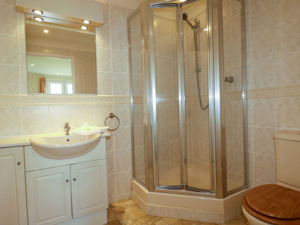 A bathroom with a shower, sink, mirror, and toilet at 4 bed number 2 Atlantic Reach near St Columb Road