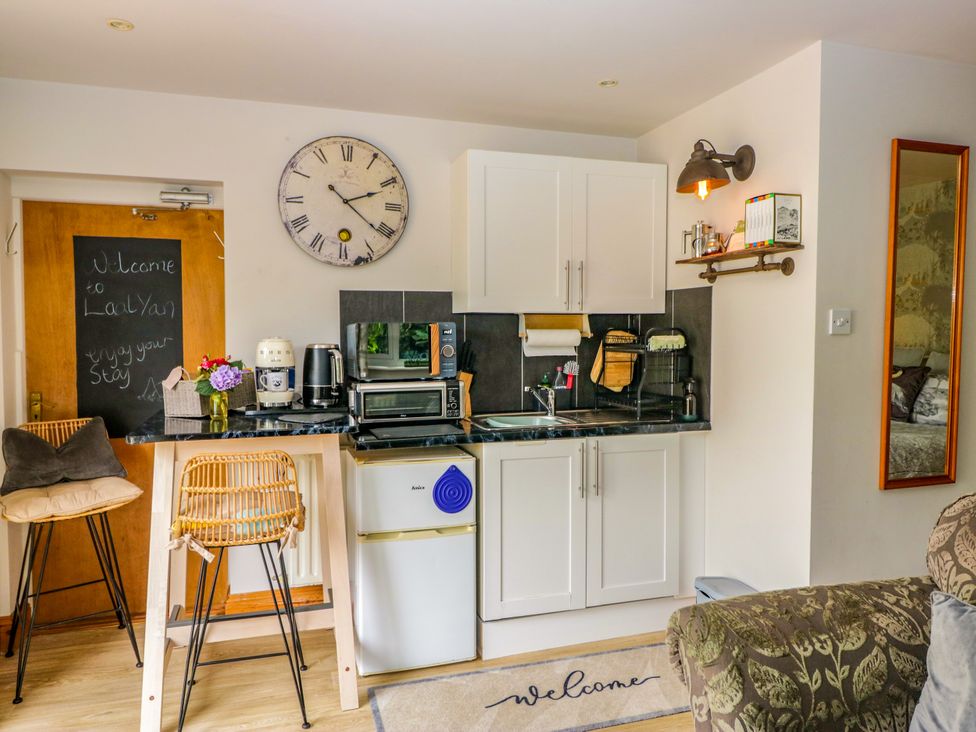 A kitchen with a clock and appliances at La'al Yan in Branthwaite