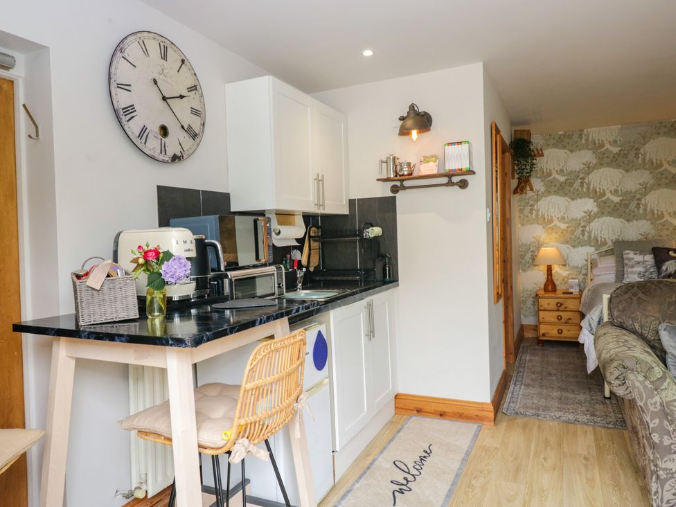 A kitchen area with a clock and appliances at La'al Yan in Branthwaite