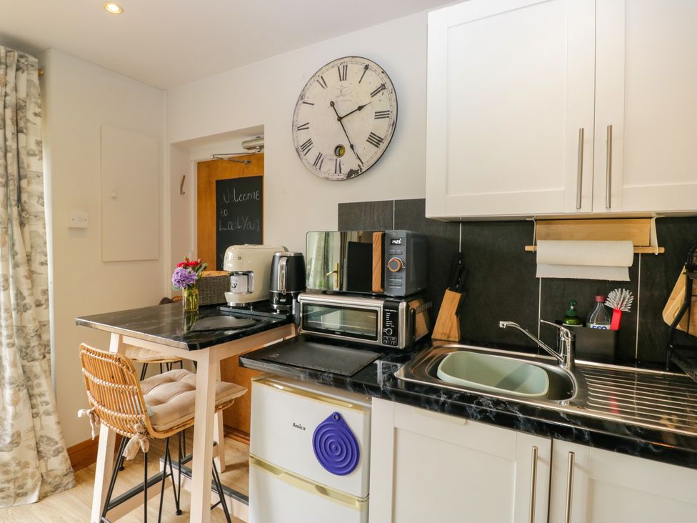 A kitchen with appliances and a bar stool at La'al Yan in Branthwaite