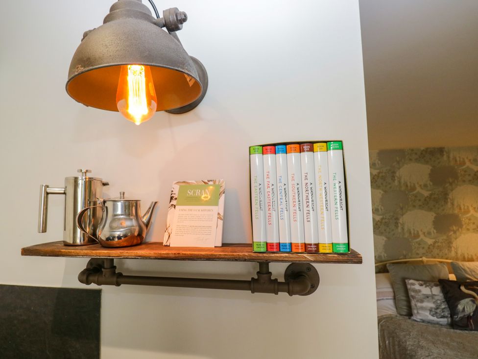 A shelf with a light fixture, teapot, coffee pot, and books at La'al Yan in Branthwaite