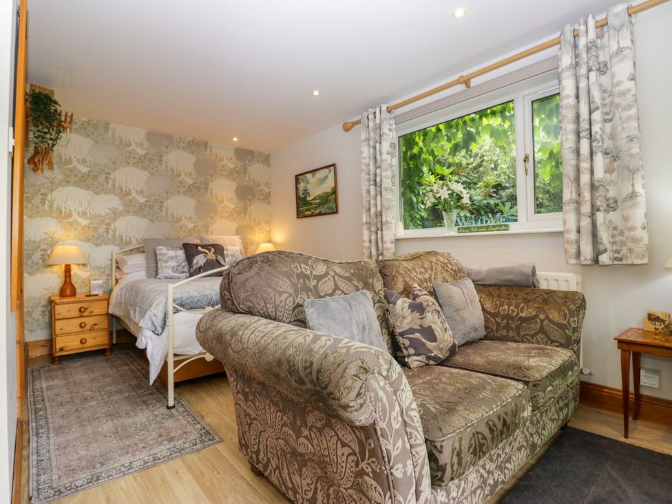 A bedroom with a bed and sofa at La'al Yan in Branthwaite