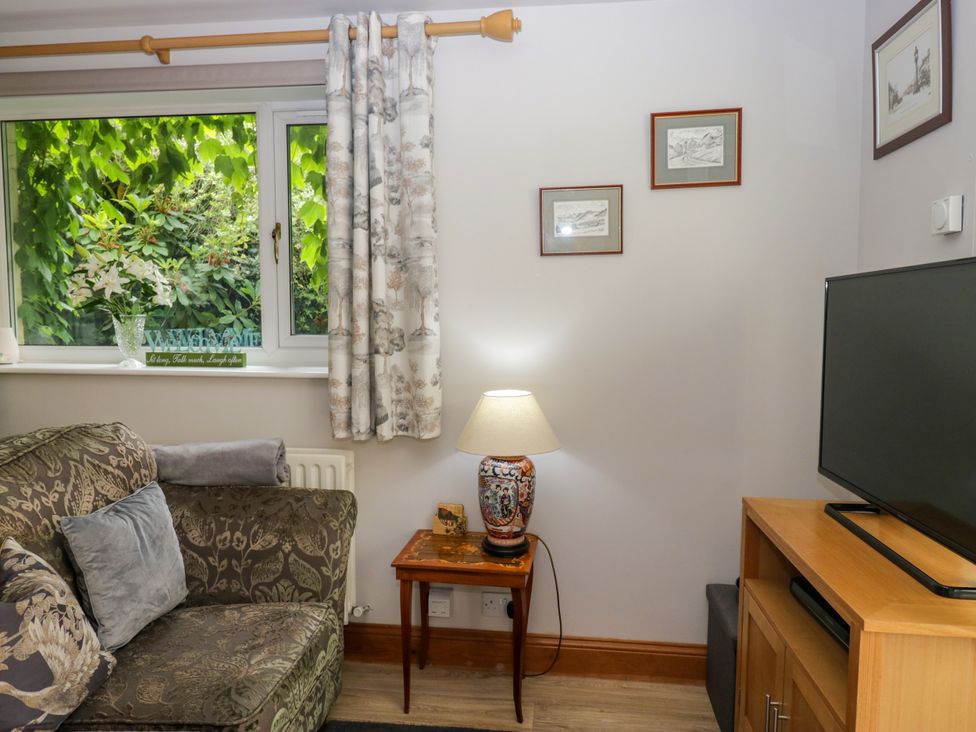 A living room with a sofa and television at La'al Yan in Branthwaite