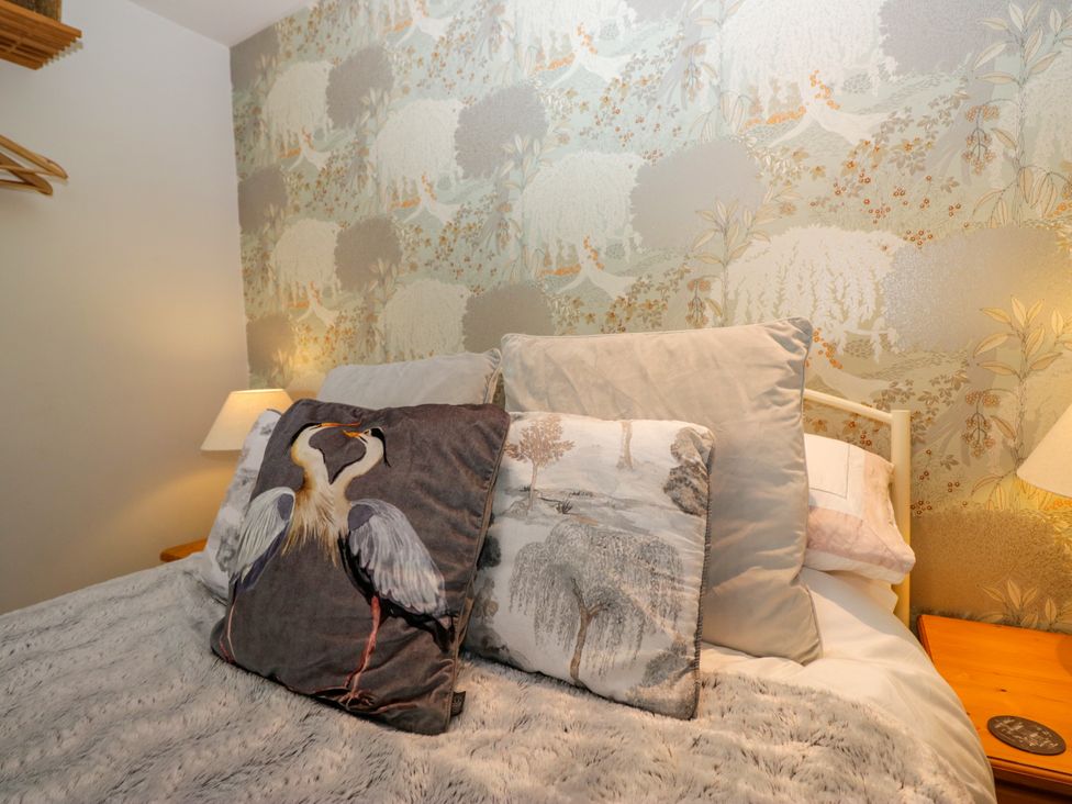 A bedroom with decorative pillows and a lamp at La'al Yan in Branthwaite