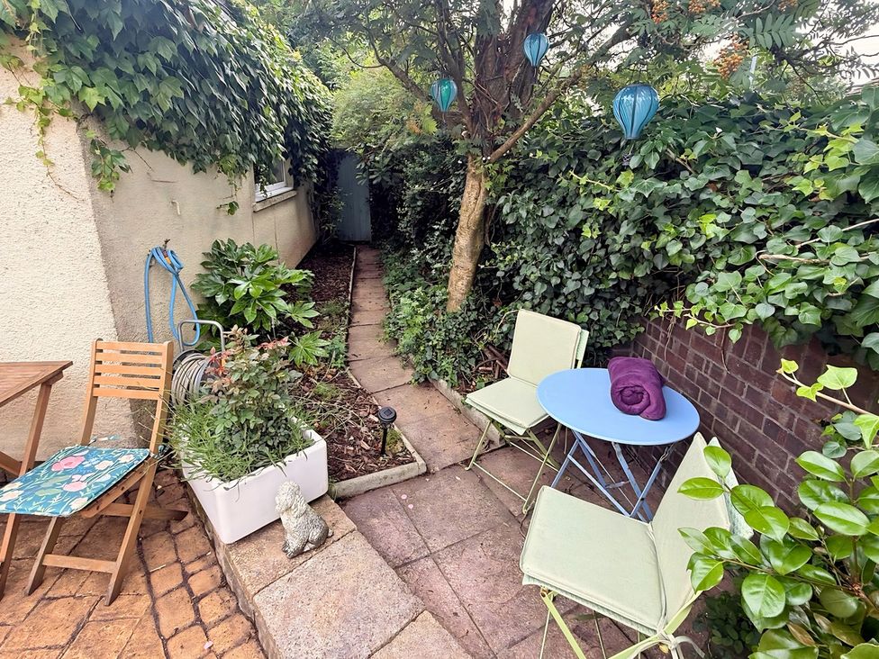 A garden with a pathway, seating area and plants at La'al Yan in Branthwaite