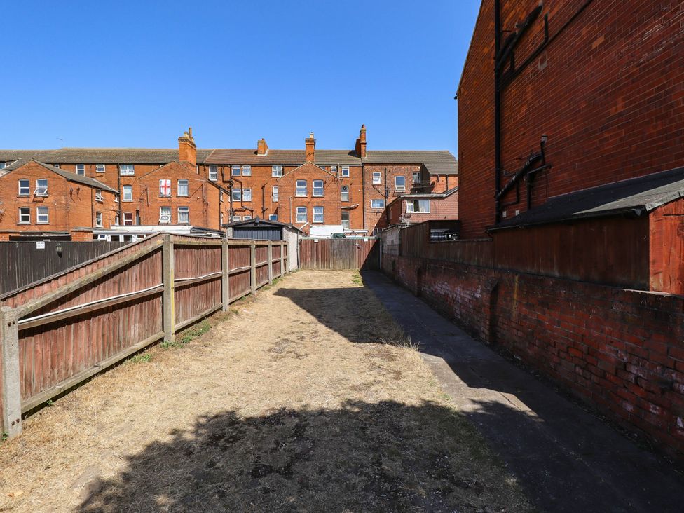 An outdoor area with a pathway between fences and buildings at The Skegness Hotel in Skegness