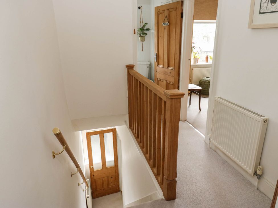 A staircase leading to a hallway with a door and a chair at 10 Park Road