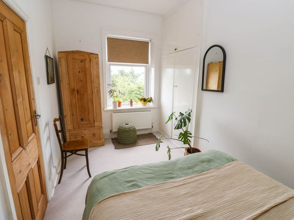 A bedroom with a bed, wardrobe, chair, and window at 10 Park Road 