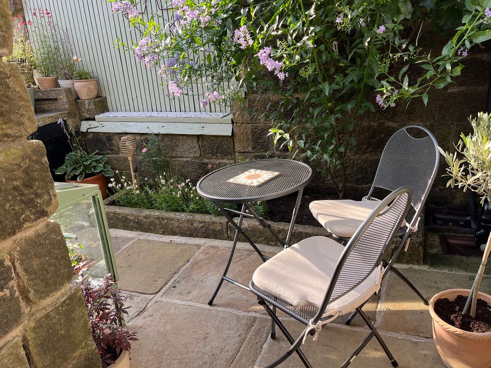 A garden with a table and chairs at Snowdrop Cottage in Cowling