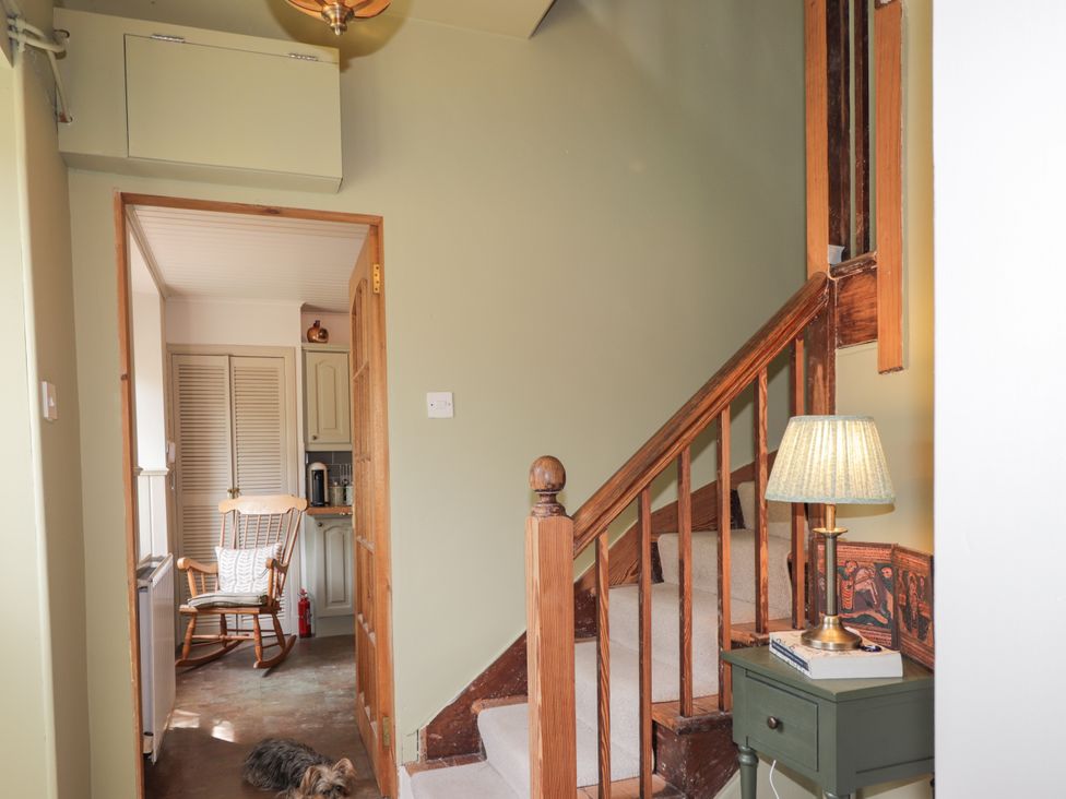 A hallway with a staircase and a rocking chair at Gairnshiel School House near Ballater