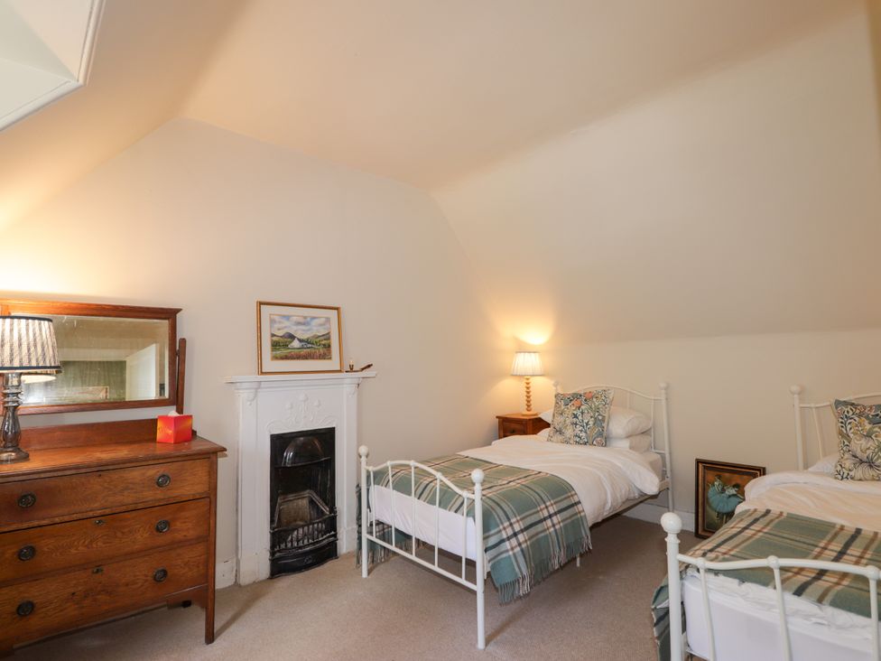 A bedroom with two beds and a fireplace at Gairnshiel School House near Ballater