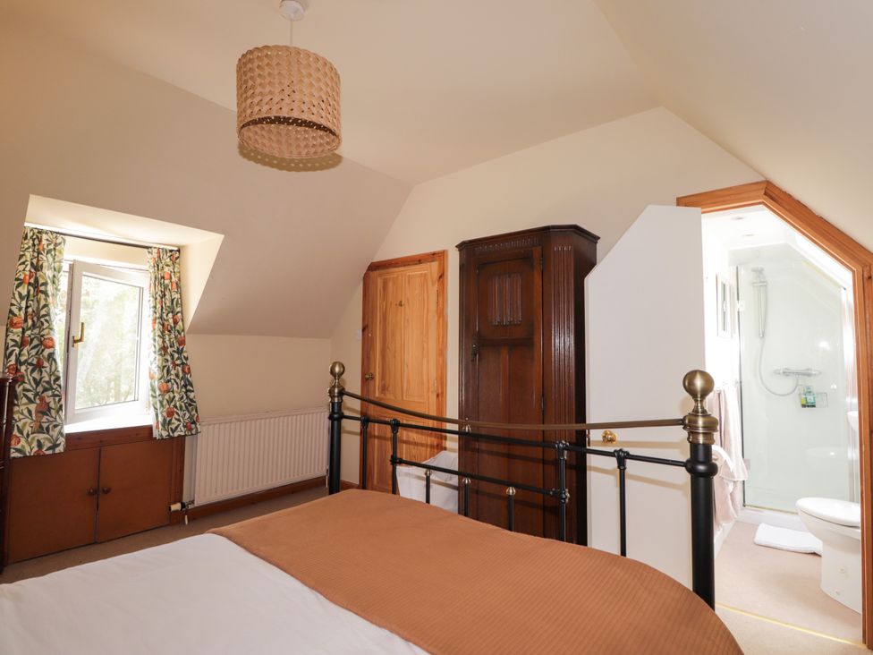 A bedroom with a bed, wardrobe and attached bathroom at Gairnshiel School House near Ballater