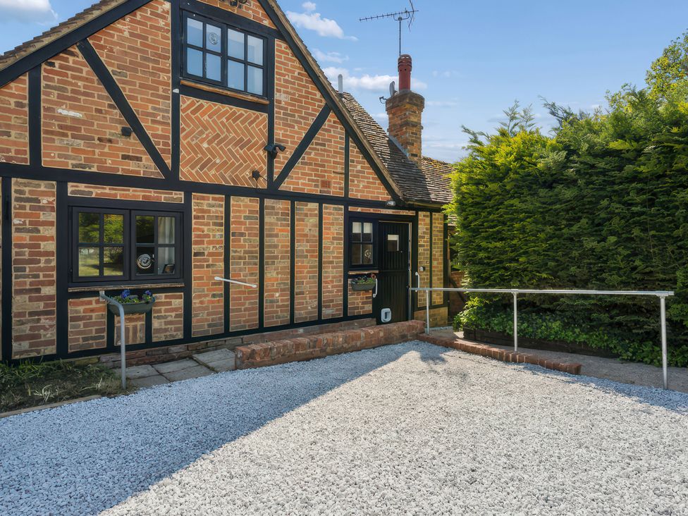 An exterior view of a house with brick walls and a gravel driveway at 5 Acres Cottage in Rickmansworth