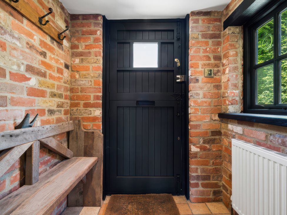 A hallway with a black door and wooden bench at 5 Acres Cottage in Rickmansworth