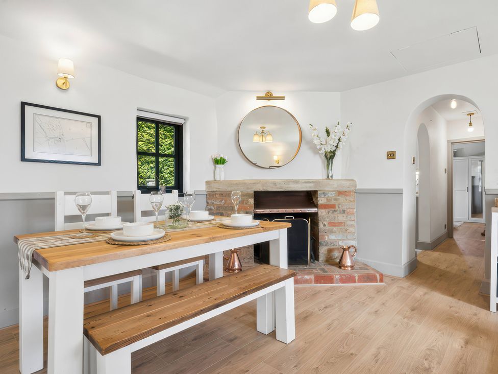 A dining room with a table, bench, and fireplace at 5 Acres Cottage in Rickmansworth