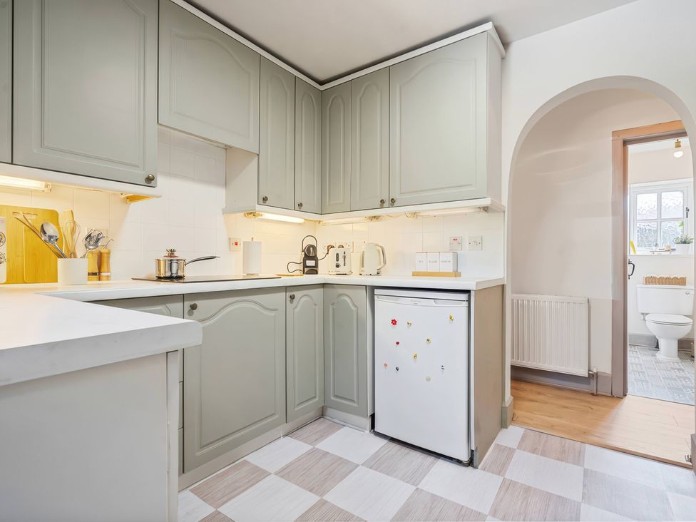 A kitchen with cabinets, stove, refrigerator, and doorway to a bathroom at 5 Acres Cottage in Rickmansworth