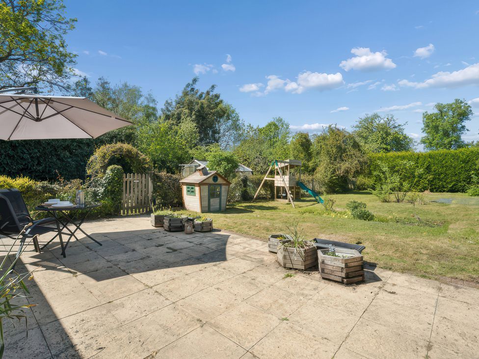 A garden with a playhouse and swing set at 5 Acres Cottage in Rickmansworth