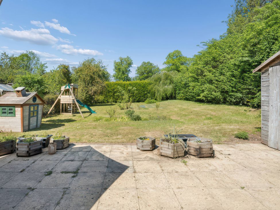 A garden with a playhouse and swing set at 5 Acres Cottage in Rickmansworth