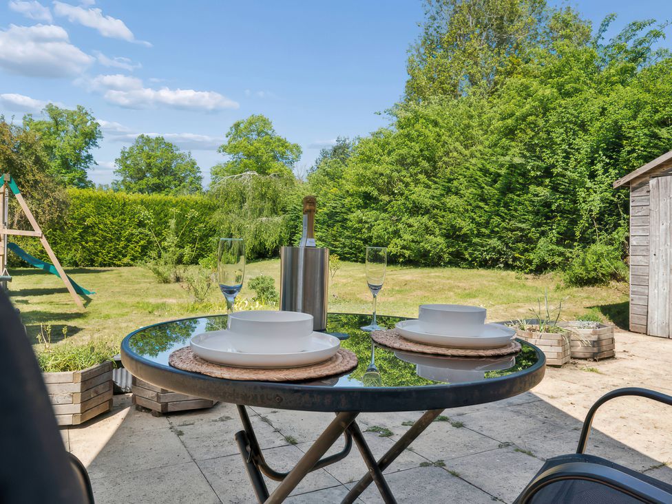 A table set with plates and wine glasses in the garden at 5 Acres Cottage in Rickmansworth