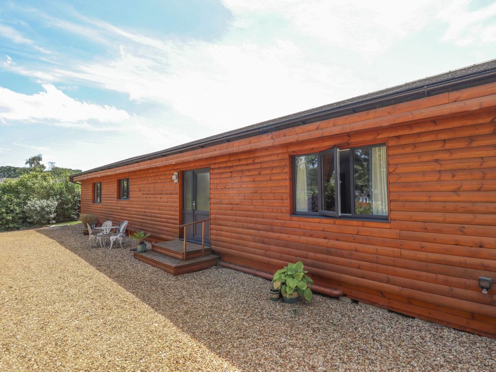 An exterior view of a wooden house with outdoor seating area at 80 Pentney Lakes Pentney near King's Lynn