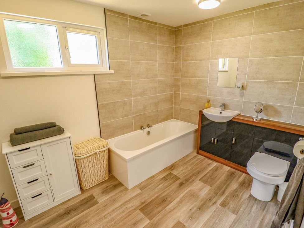 A bathroom with a bathtub, toilet, sink and storage cabinet at 80 Pentney Lakes Pentney near King's Lynn