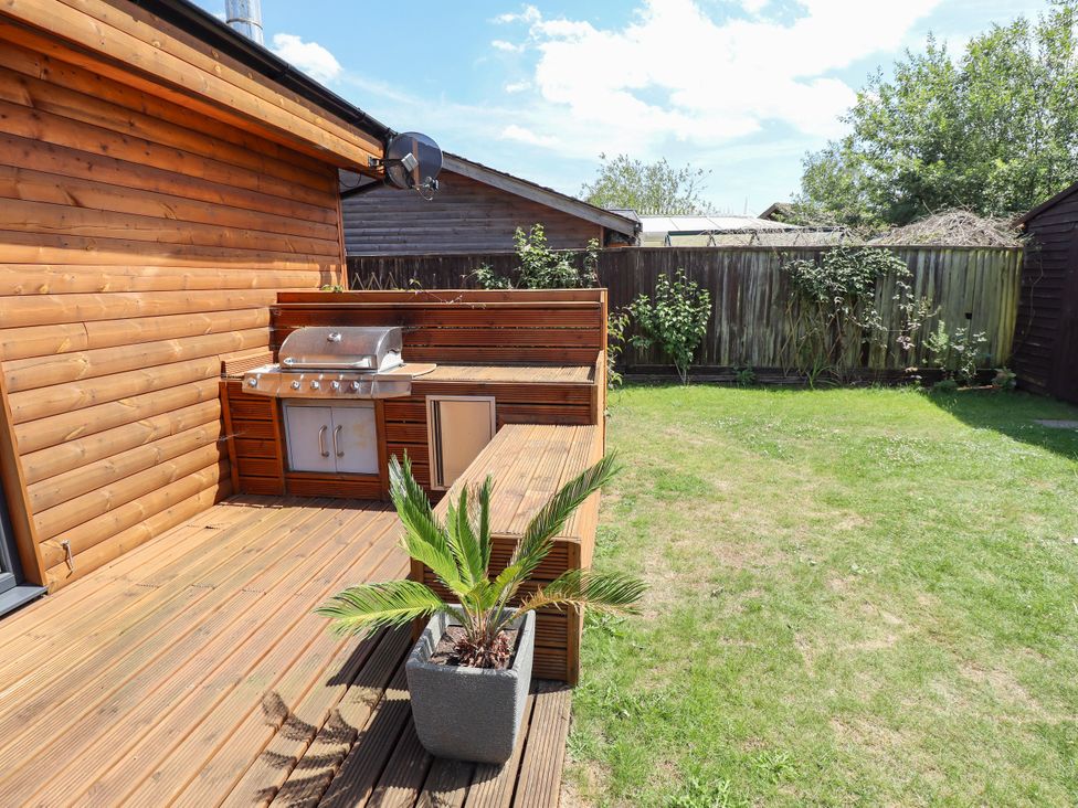 A garden with a grill and decking at 80 Pentney Lakes in Pentney near King's Lynn