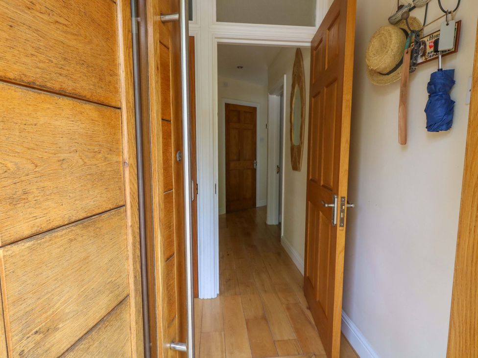 A hallway with wooden doors and a mirror at Little Gem in Weymouth