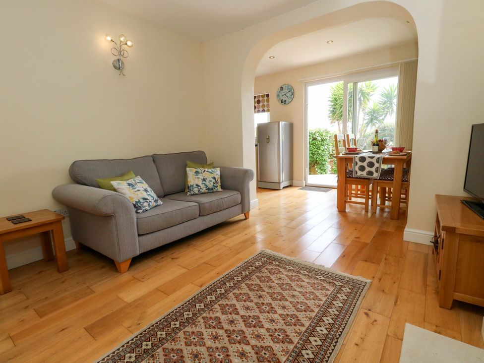 A living room with a sofa and dining area at Little Gem in Weymouth