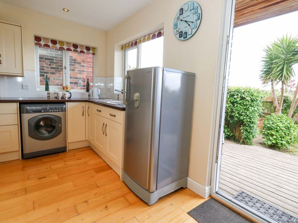 A kitchen with a refrigerator and washing machine at Little Gem in Weymouth