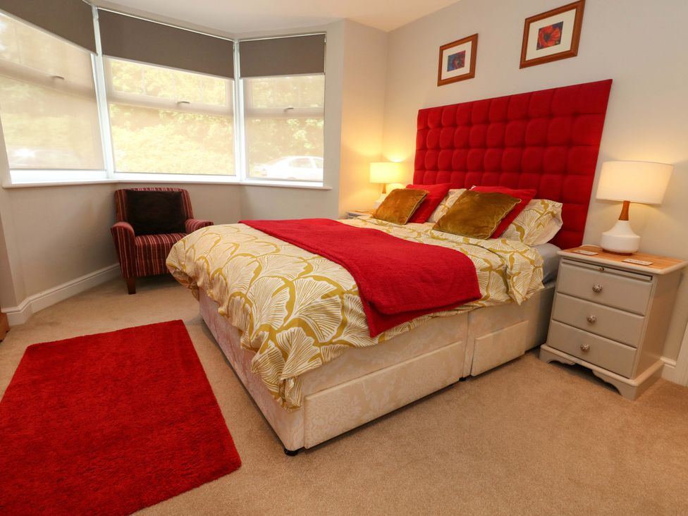 A bedroom with a bed, bedside table, and armchair at Little Gem in Weymouth