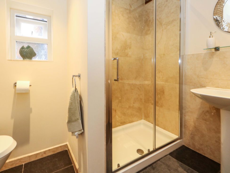 A bathroom with a shower, toilet, and sink at Little Gem in Weymouth