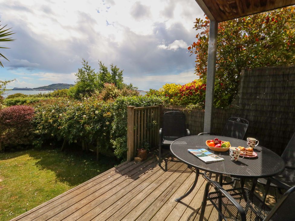 A seating area with a table and chairs and fruit at Little Gem in Weymouth