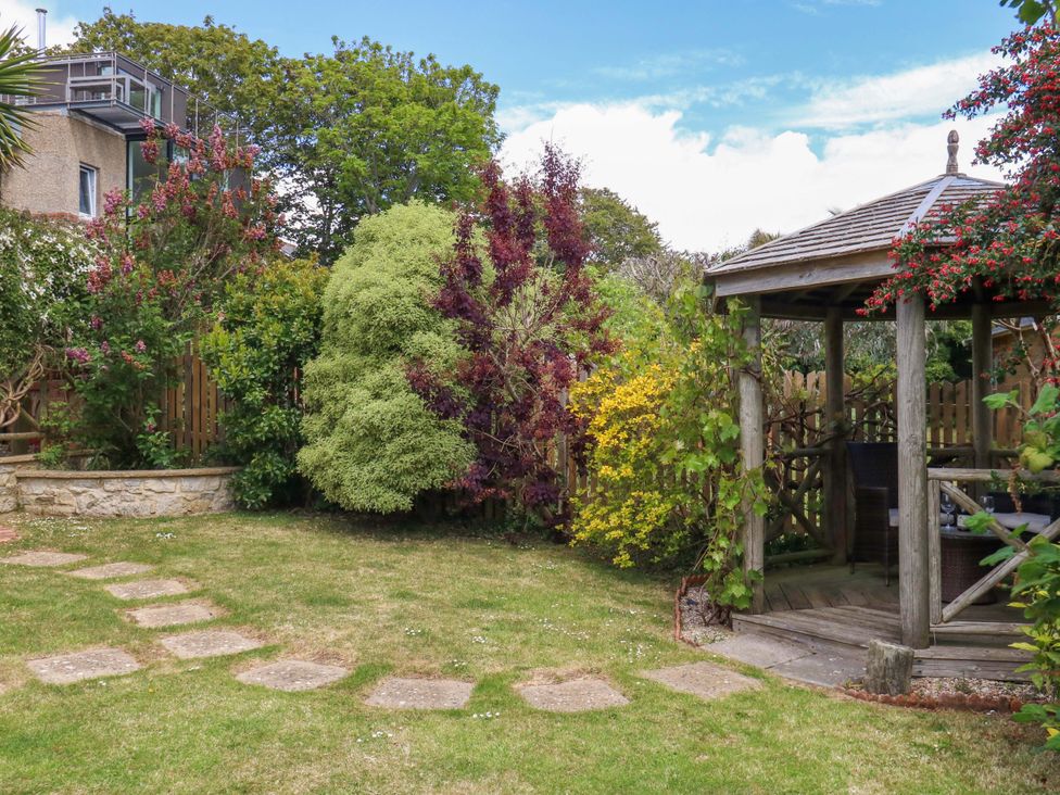 A garden with a gazebo and pathway at Little Gem in Weymouth