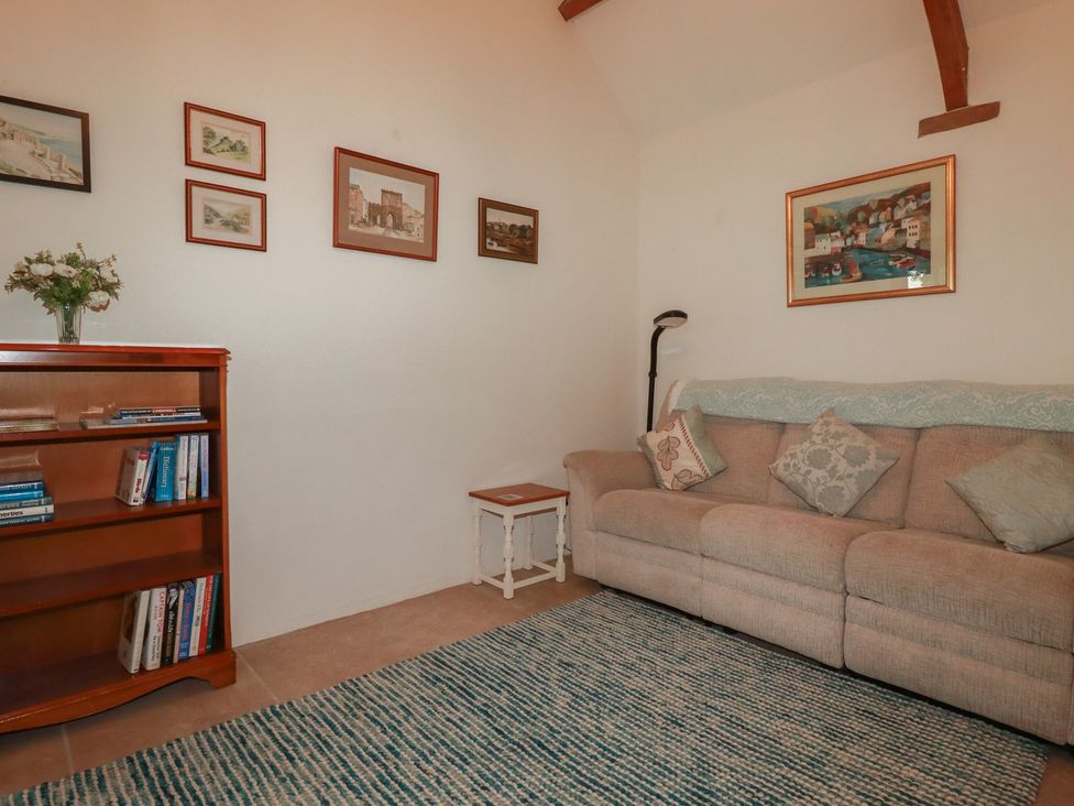 A living room with a couch and bookshelf at Cider Cottage
