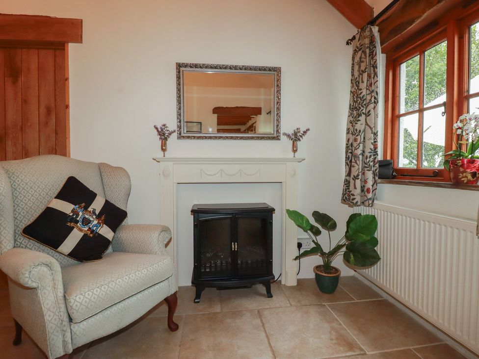 A living room with an armchair and a fireplace at Cider Cottage