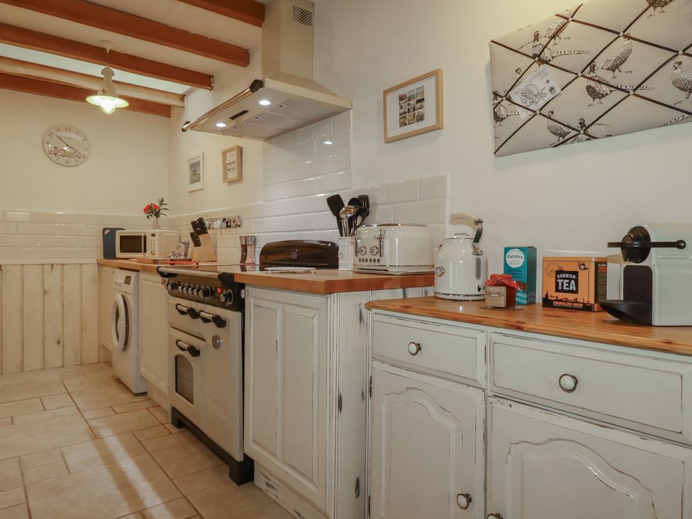 A kitchen with appliances and cabinets at Cider Cottage