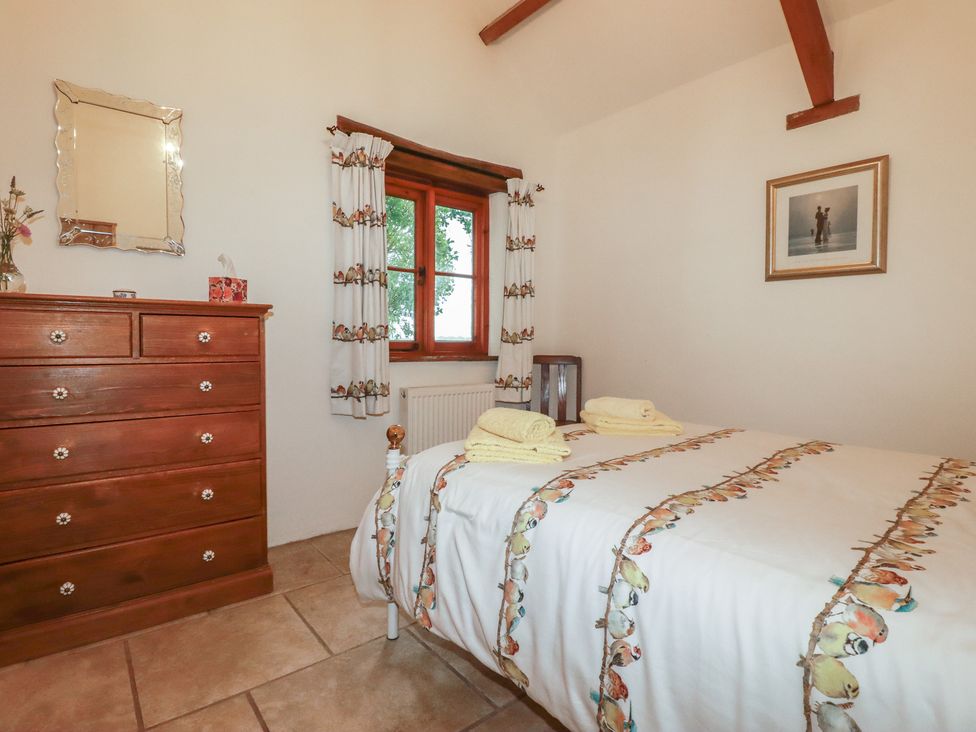 A bedroom with a bed and dresser at Cider Cottage 