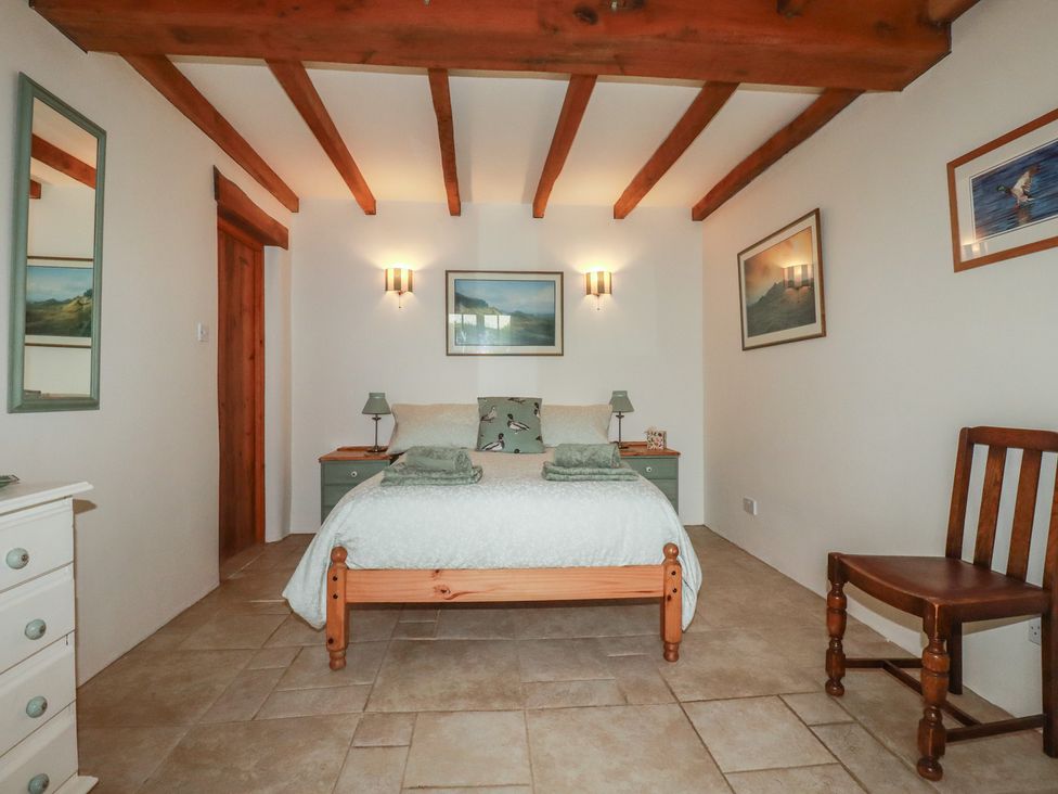 A bedroom with a bed and chair at Cider Cottage