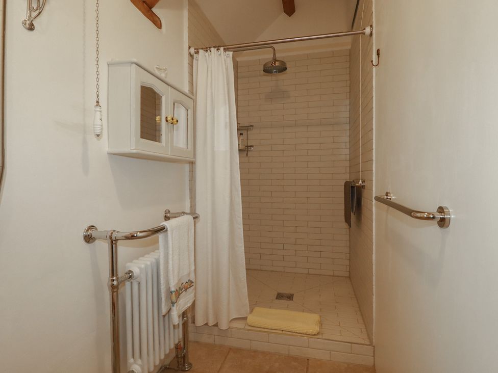 A bathroom with a shower and towel rack at Cider Cottage