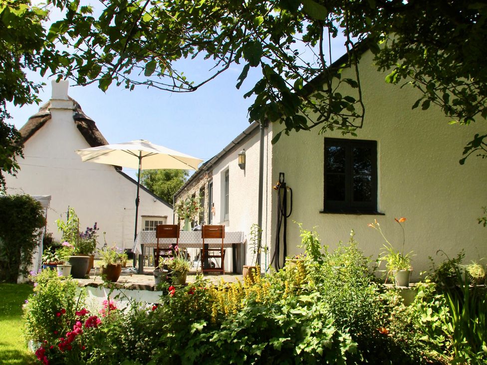A garden with a table and chairs under an umbrella at Cider Cottage near Launceston