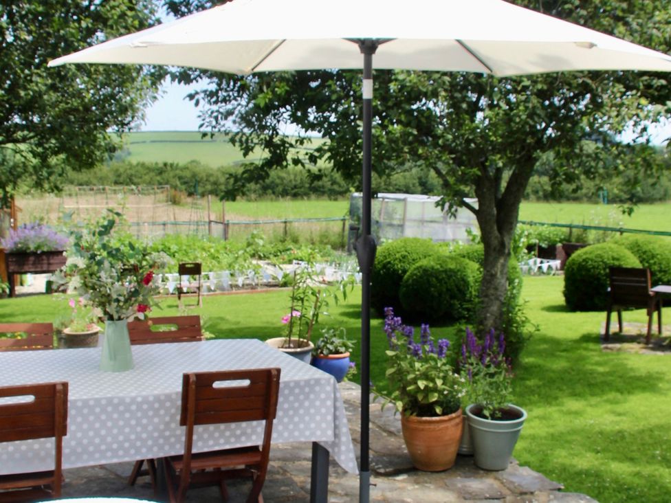 A garden with a table and chairs under an umbrella at Cider Cottage near Launceston